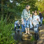 Kinder die am Bach mit Köchern fischen