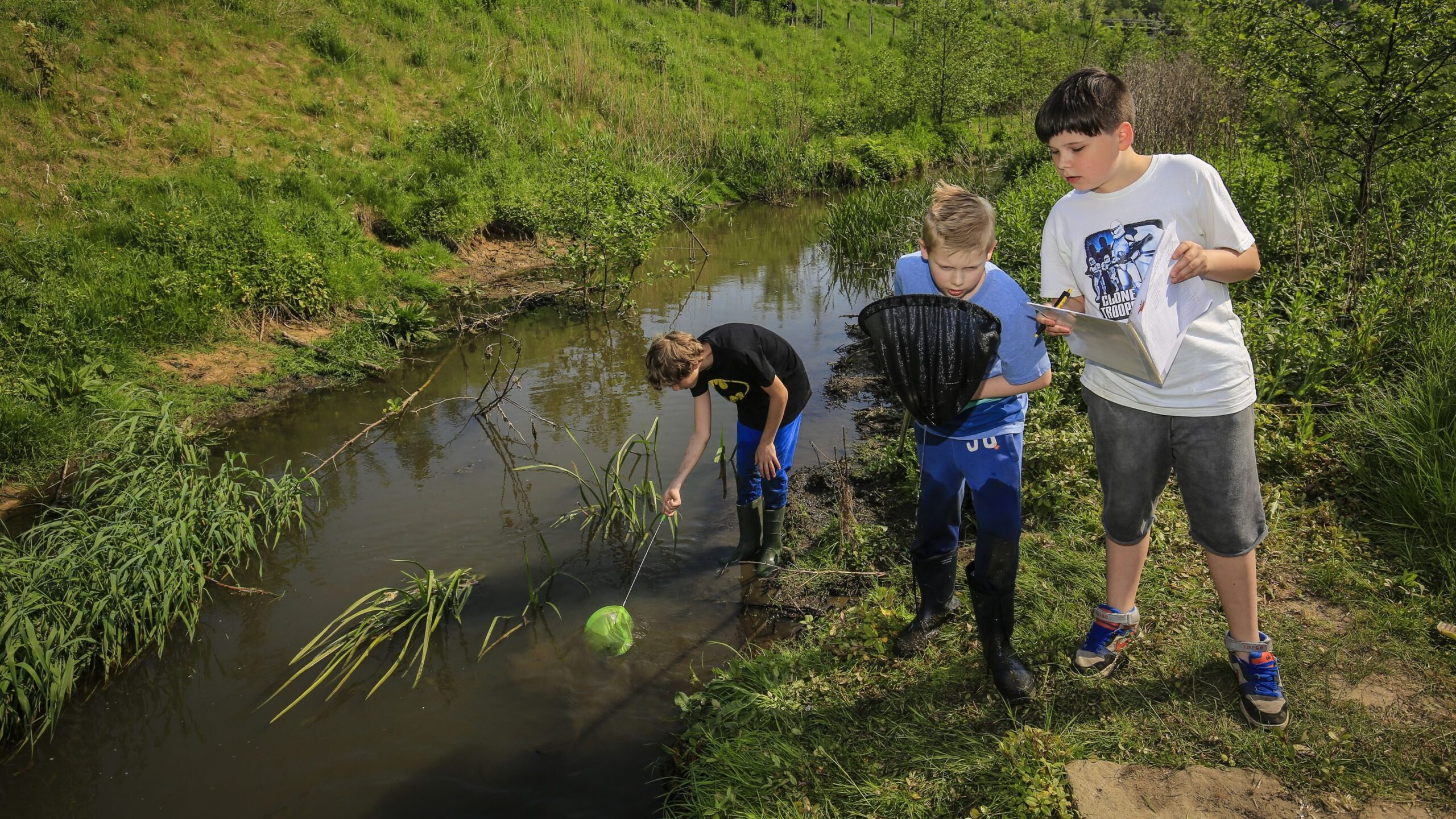 Drei Jungen fischen mit Köchern in der Emscher